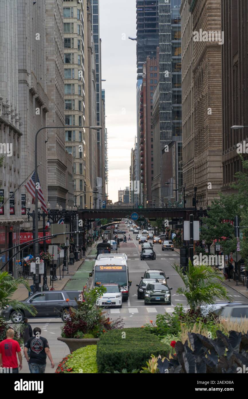 Chicago, Illinois, USA - Circa 2019: Vertical view down street in downtown Chicago during day time morning commute past  L  train track overhead loop Stock Photo