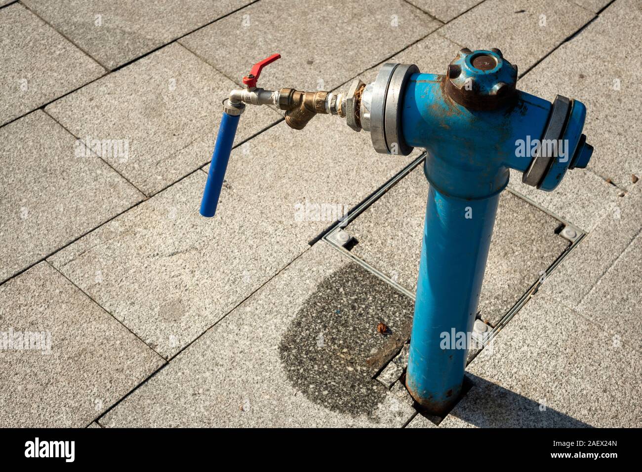 Blue fire hydrant with attached simple DIY hose and tap, Bulgaria Stock