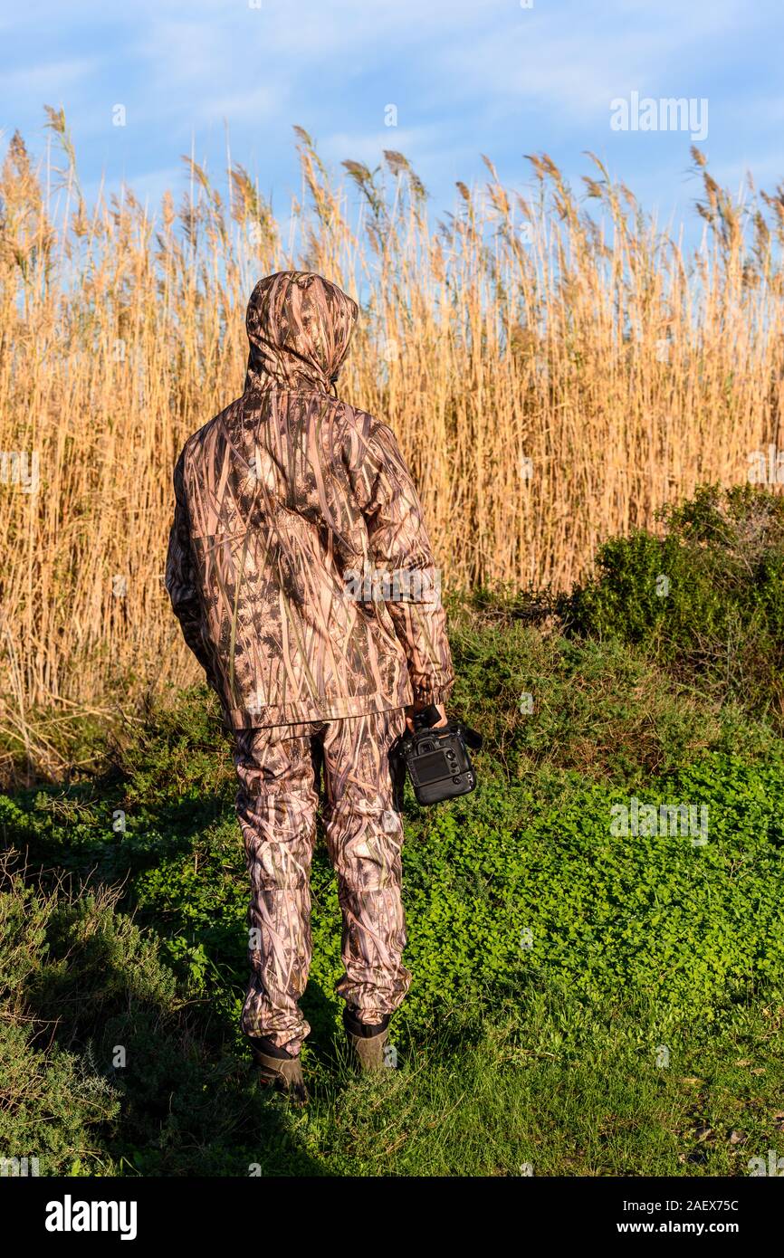 Naturalist photographer in action, with camouflage and camera, in the