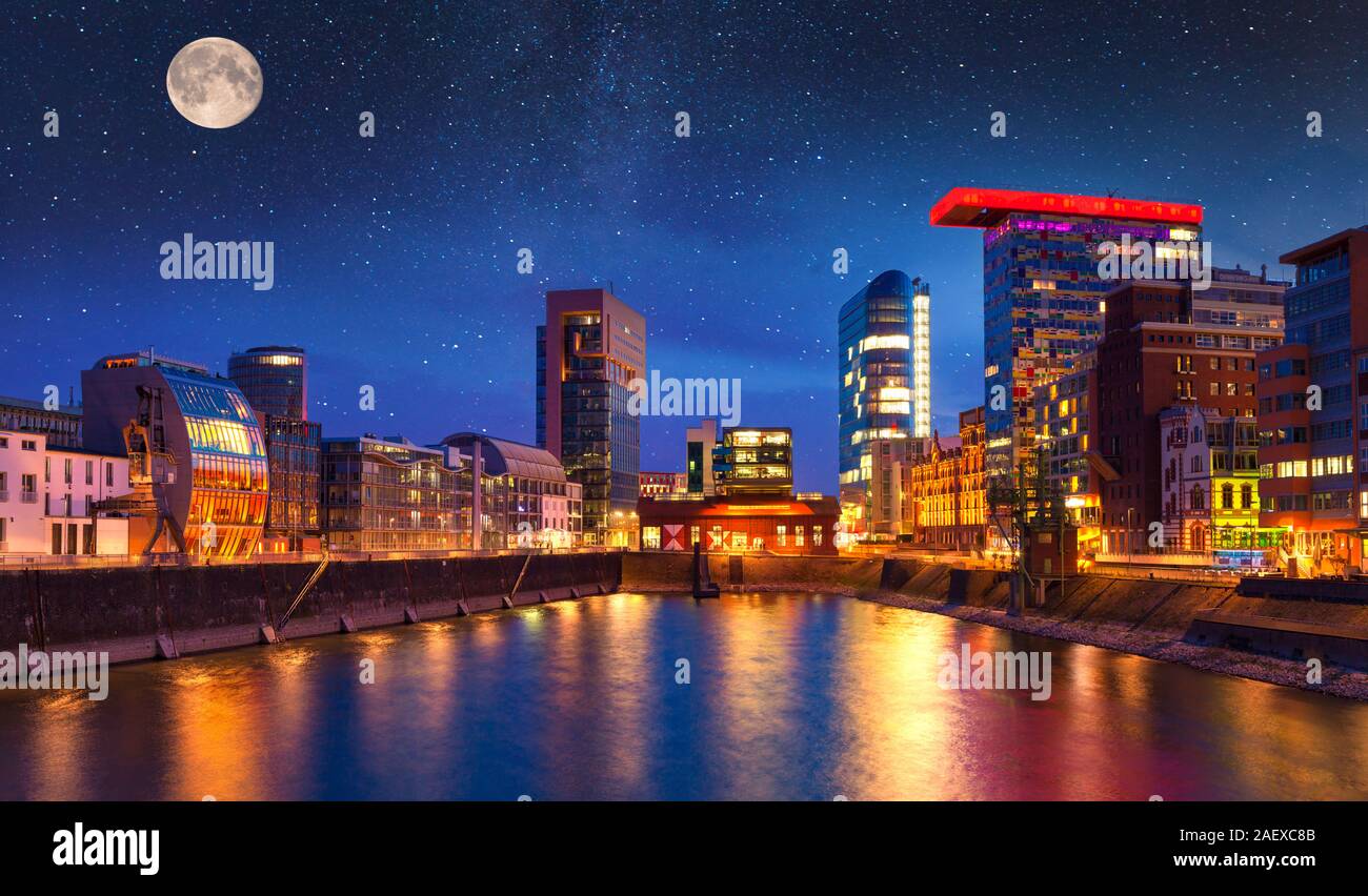 Colorful night scene of Rhein river at night in Dusseldorf. Medienhafen in the soft night light with stars and full moon, Nordrhein-Westfalen, Germany Stock Photo