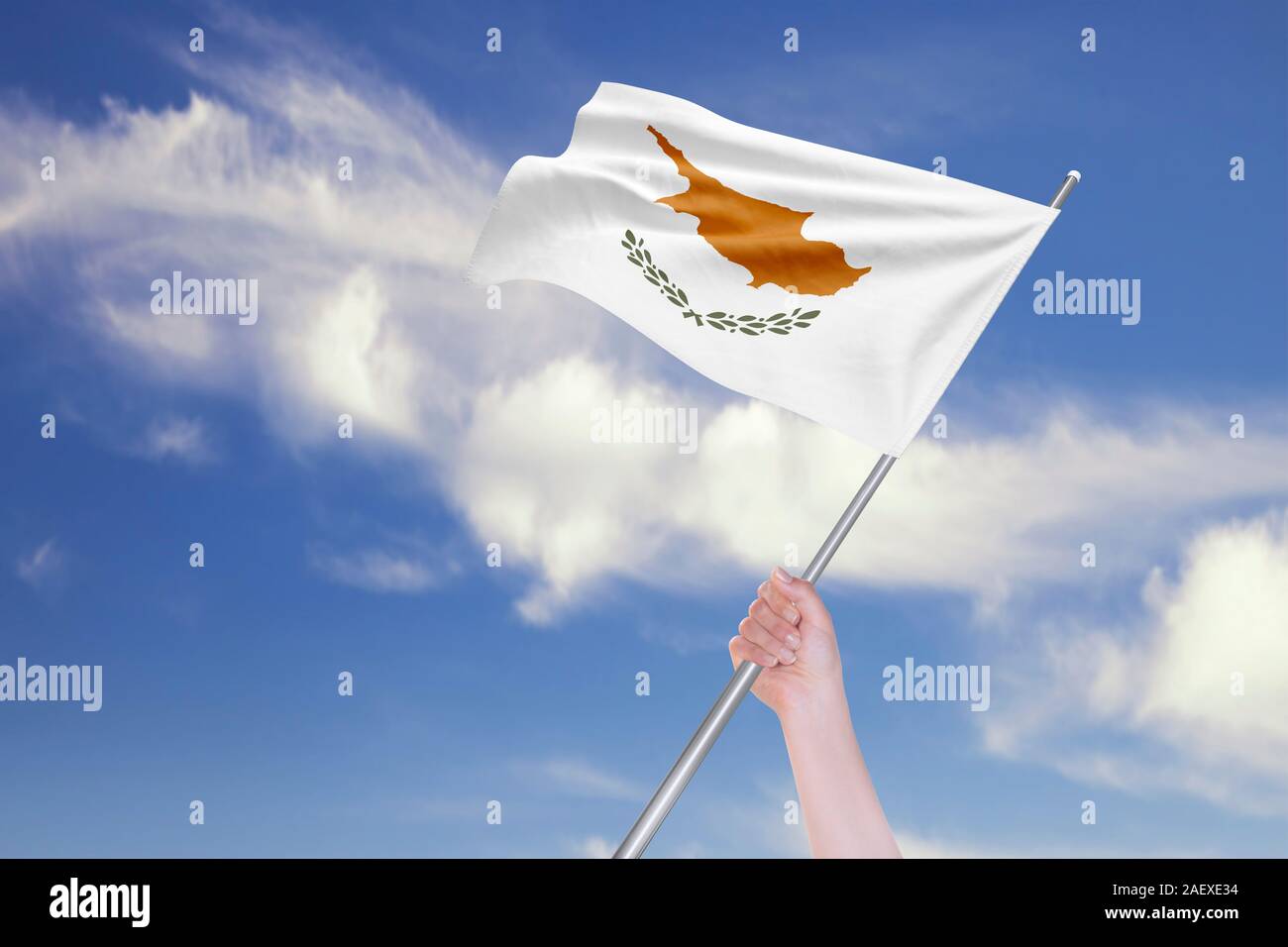 Female hand is waving Cyprus Flag against blue sky with clouds ...