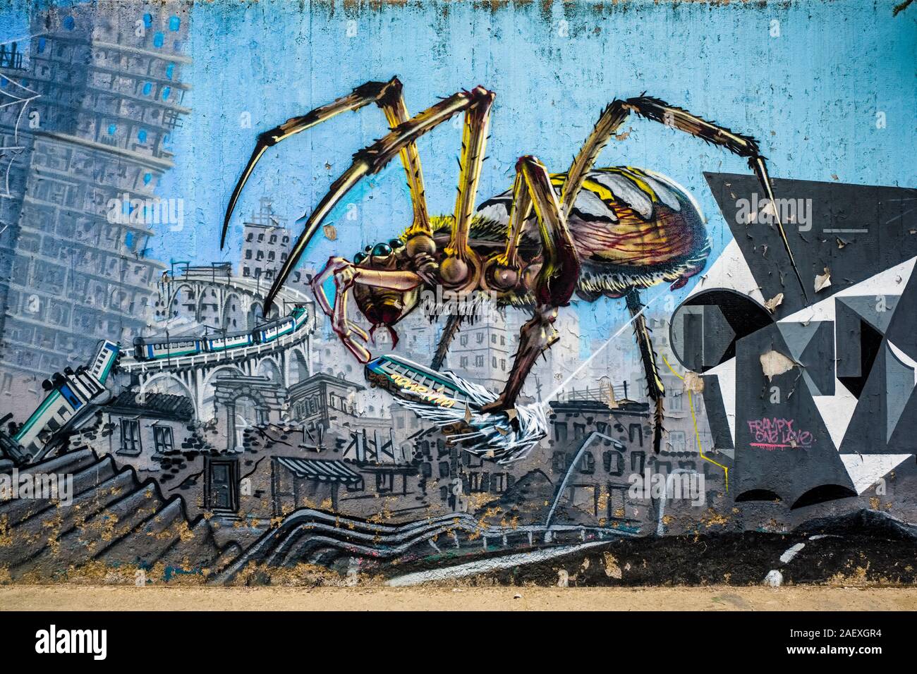 Colorful graffiti of an insect destroying a city sprayed onto a wall Stock Photo