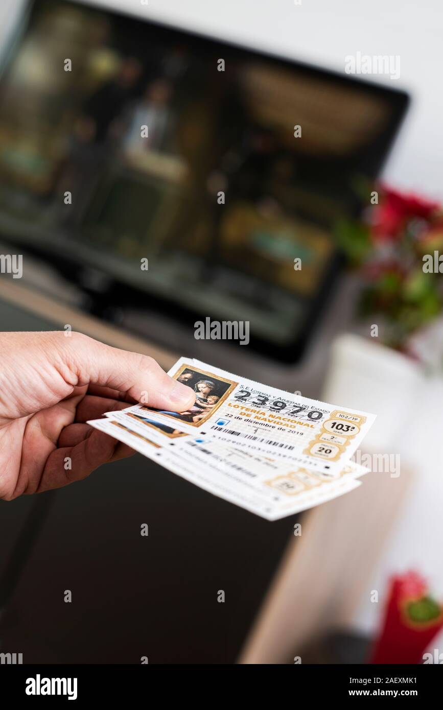 BARCELONA, SPAIN - DESEMBER 11, 2019: Closeup of a man with some tickets of the Spanish Christmas Lottery in his hand while is watching the televised Stock Photo