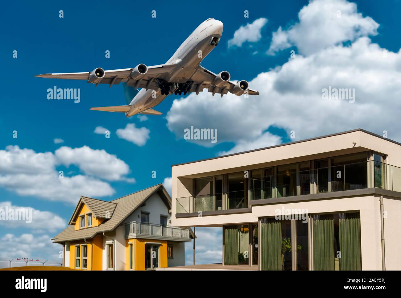 Houses with blue sky, clouds and airplane in the background Stock Photo