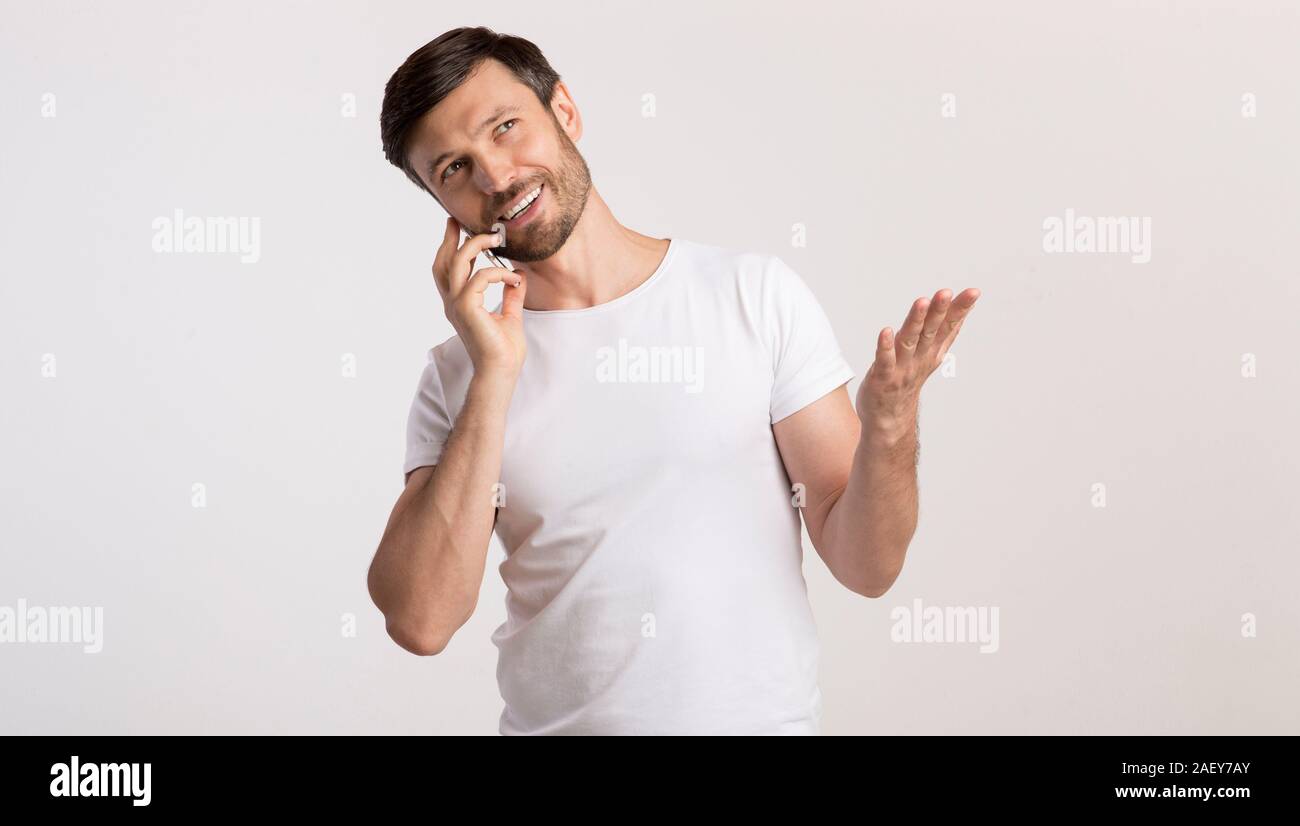 Phone Conversation. Middle-Aged Man Talking On Cellphone Gesturing And Smiling Standing On White Studio Background. Panorama Stock Photo