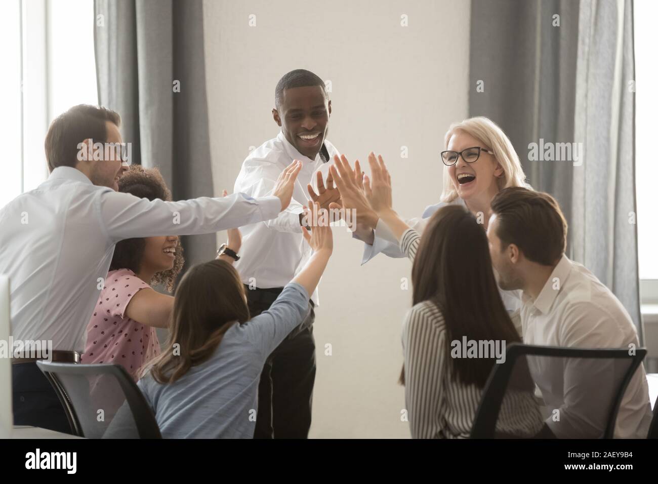 Excited multiracial colleagues give high five motivated for success ...