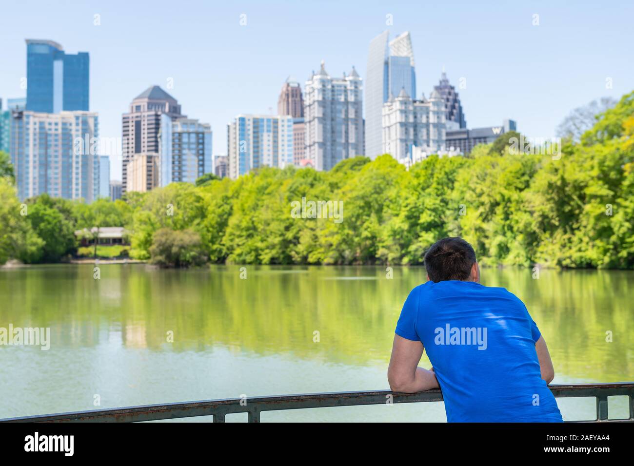 Man leaning on railing in Piedmont Park in Atlanta, Georgia looking at scenic landscape view of cityscape, skyline of urban city skyscrapers downtown Stock Photo