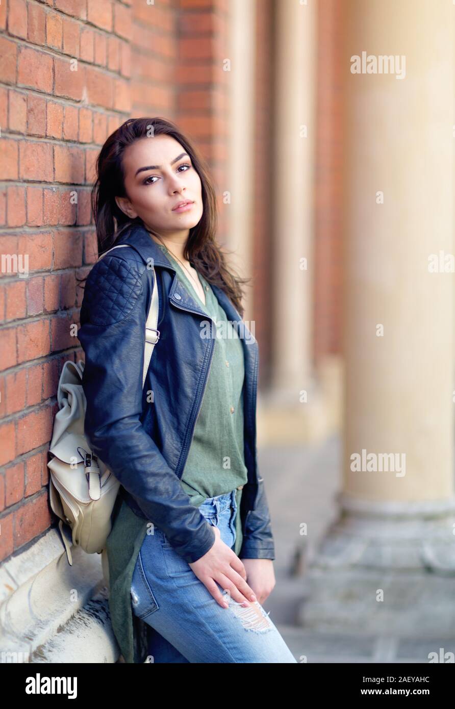 Young woman sitting against the wall. Urban Portrait Stock Photo