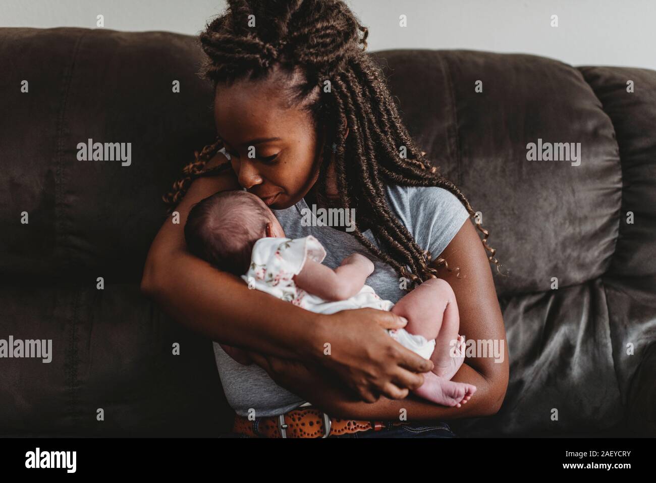 Loving ethnic mother with braids experiencing the new baby scent Stock Photo