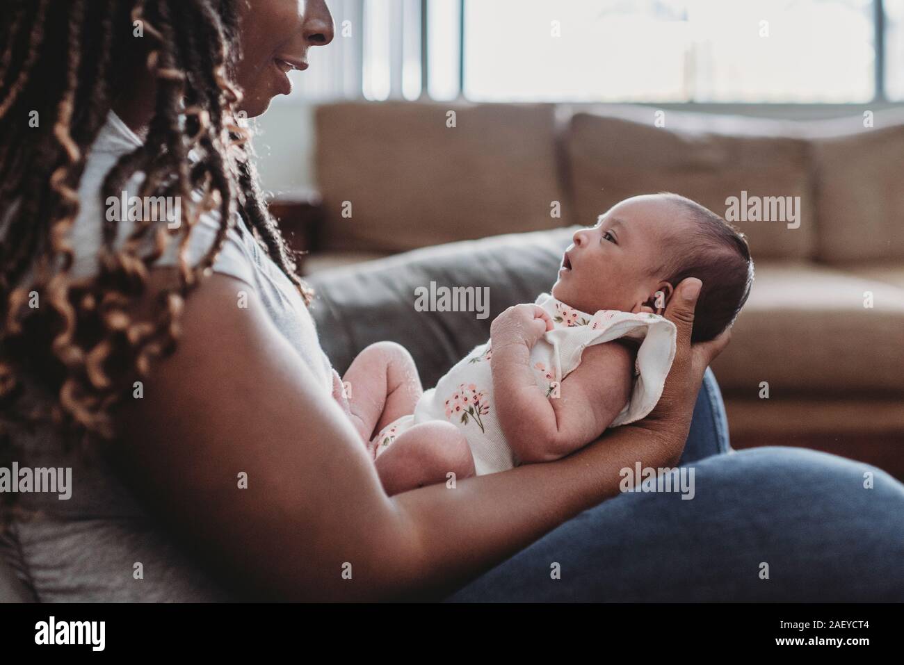 Multiracial infant held in the lap of ethnic mom with long braids Stock Photo