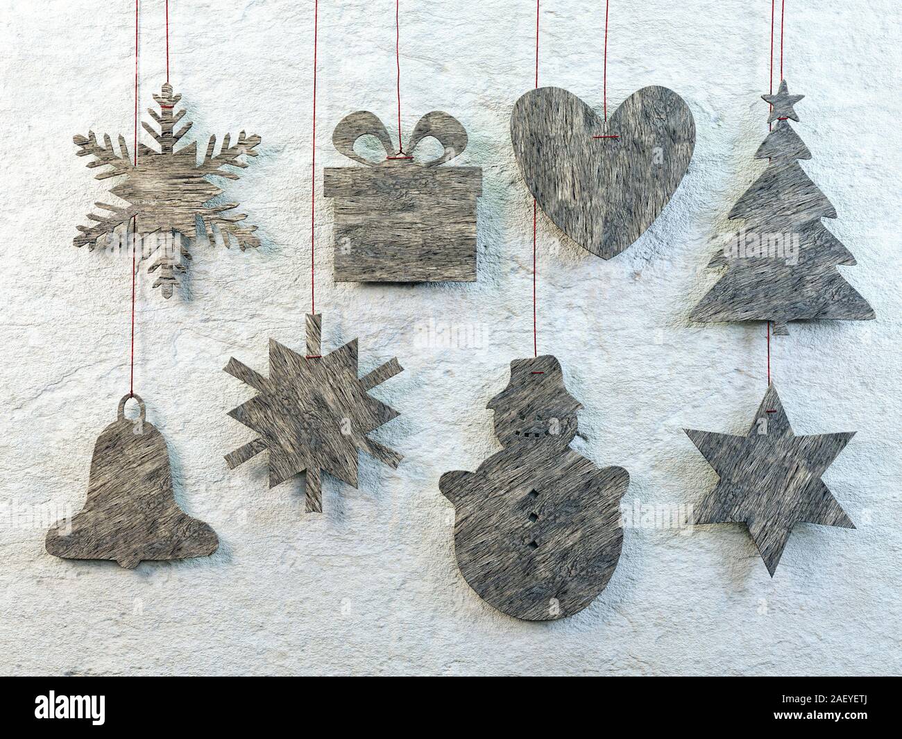 Assorted wooden christmas shapes hanging against the wall on red strings Stock Photo