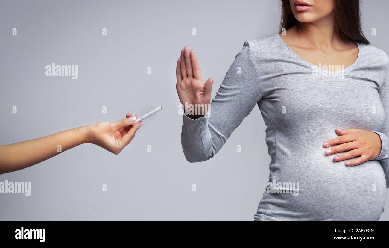 Smoking And Pregnancy. Pregnant woman refusing to take cigarette, grey
