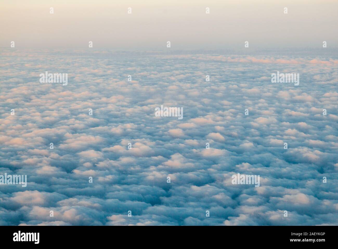 flying above the clouds at sunset landscape from an airplane Stock Photo