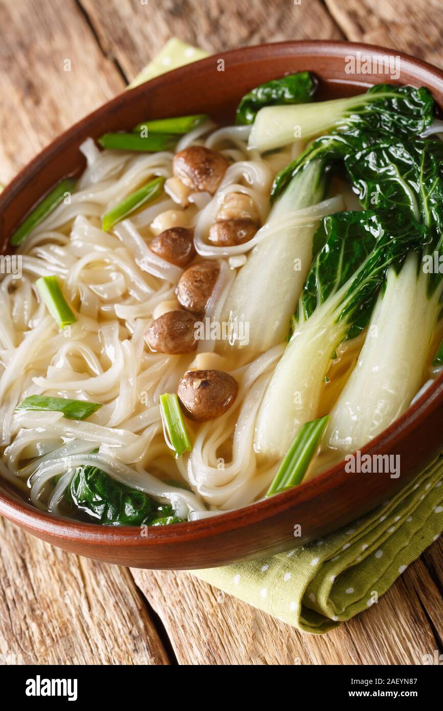 Asian rice noodle soup with mushrooms and bok choy closeup in a bowl on
