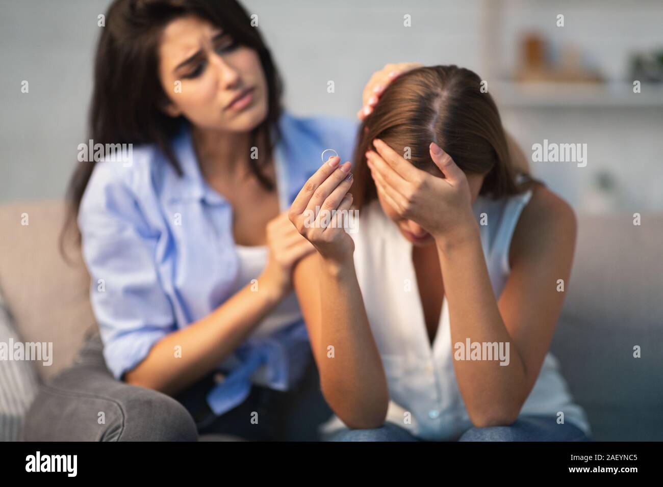 Divorce Concept. Friend Comforting Desperate Girl After Breakup With ExHusband Holding Ring