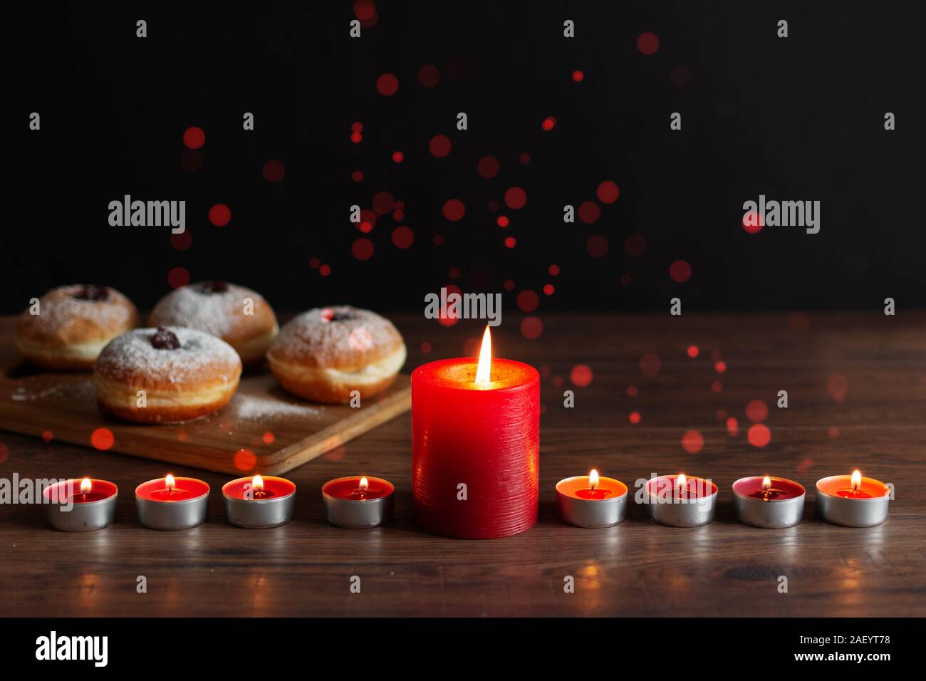 Menorah with candles (traditional Candelabra) and traditional donuts sufganiyot on wooden table for Hanukkah celebration. Stock Photo