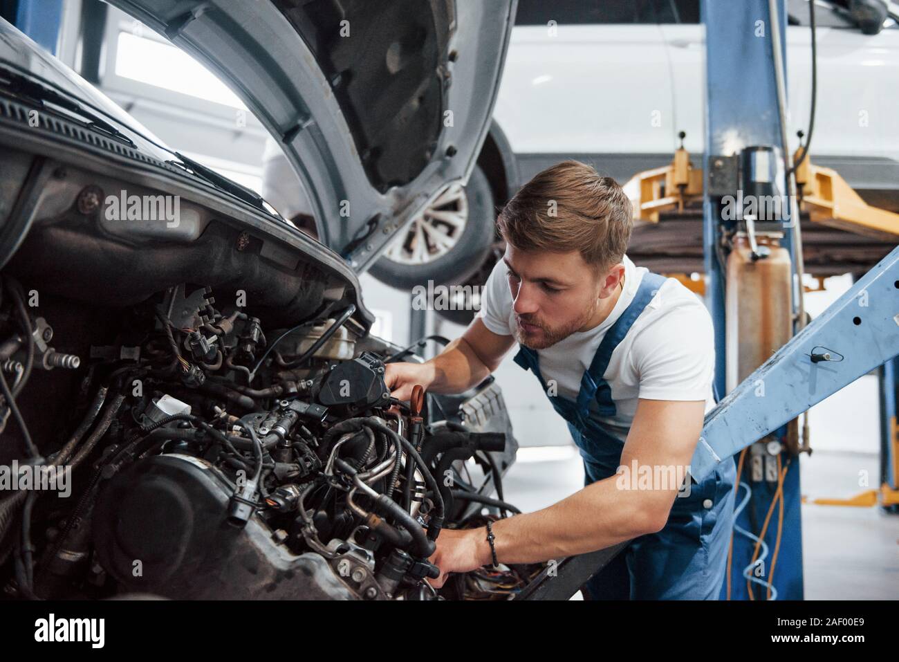 Male mechanic on the job. Employee in the blue colored uniform works in