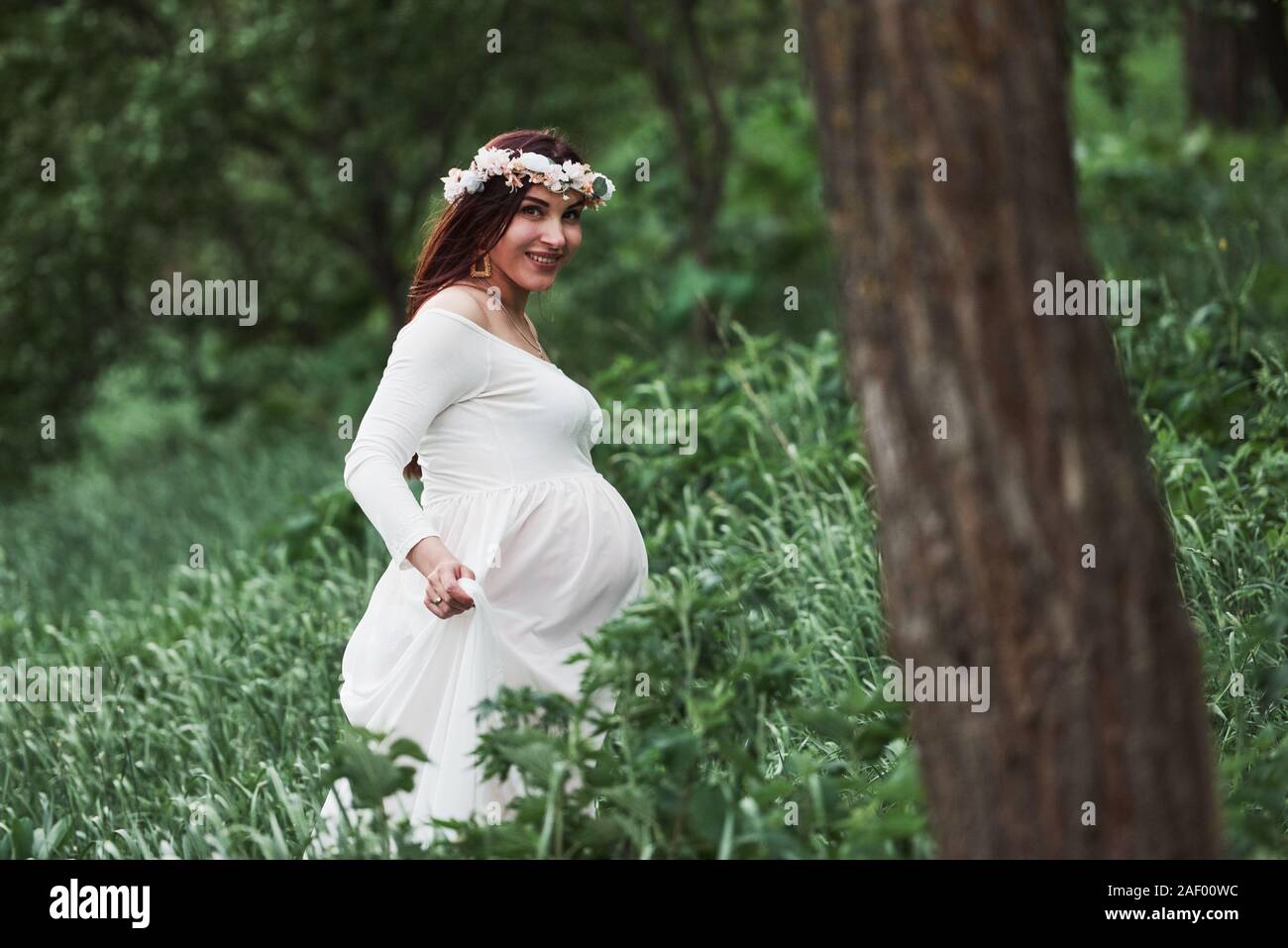 Having good time. Beautiful pregnant woman in dress have a walk outdoors. Positive brunette Stock Photo
