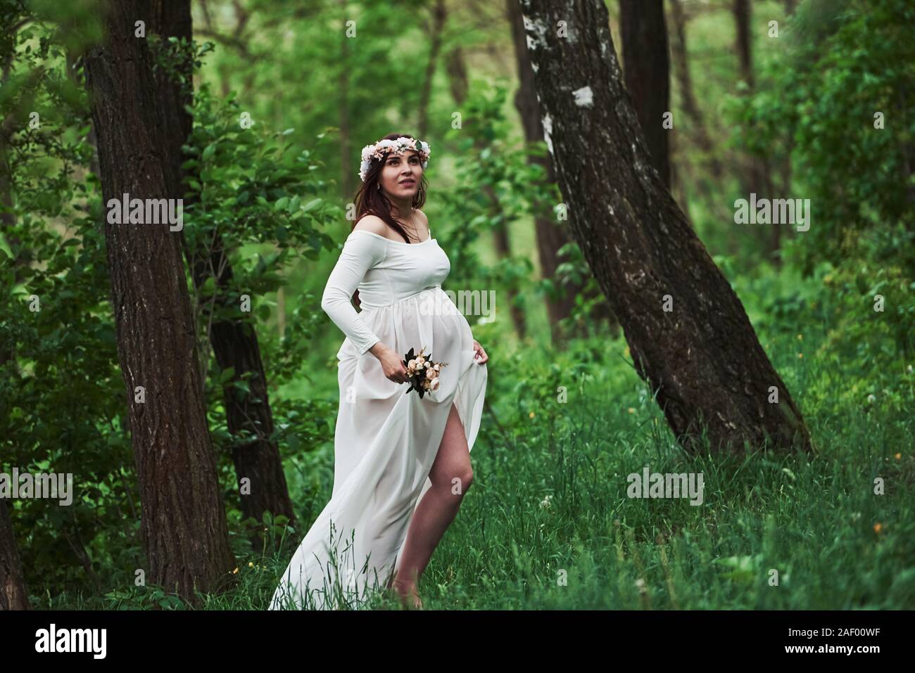 Power of nature. Beautiful pregnant woman in dress have a walk outdoors ...