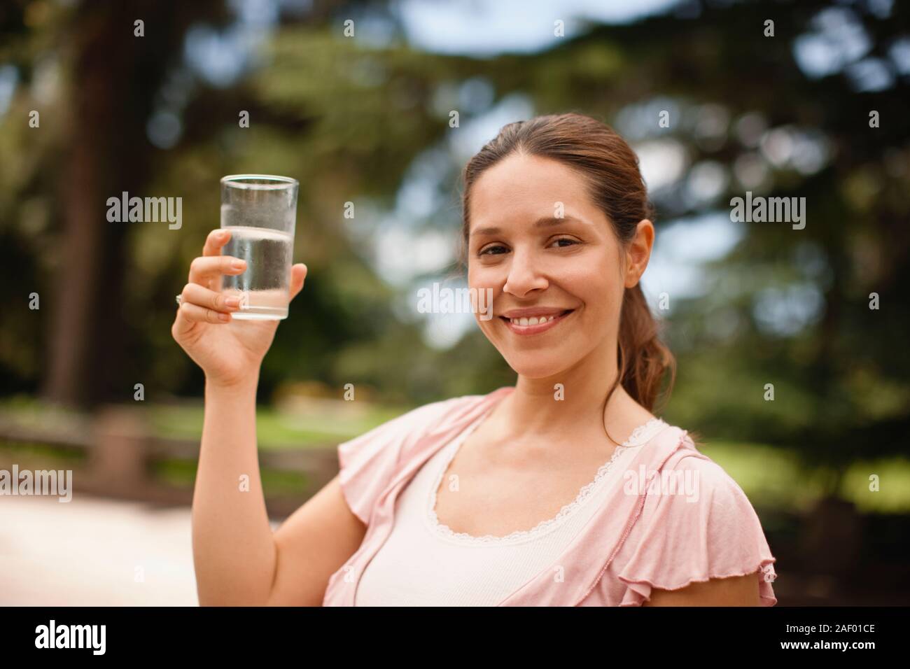 Twenty something woman holds up a glass of water. Stock Photo
