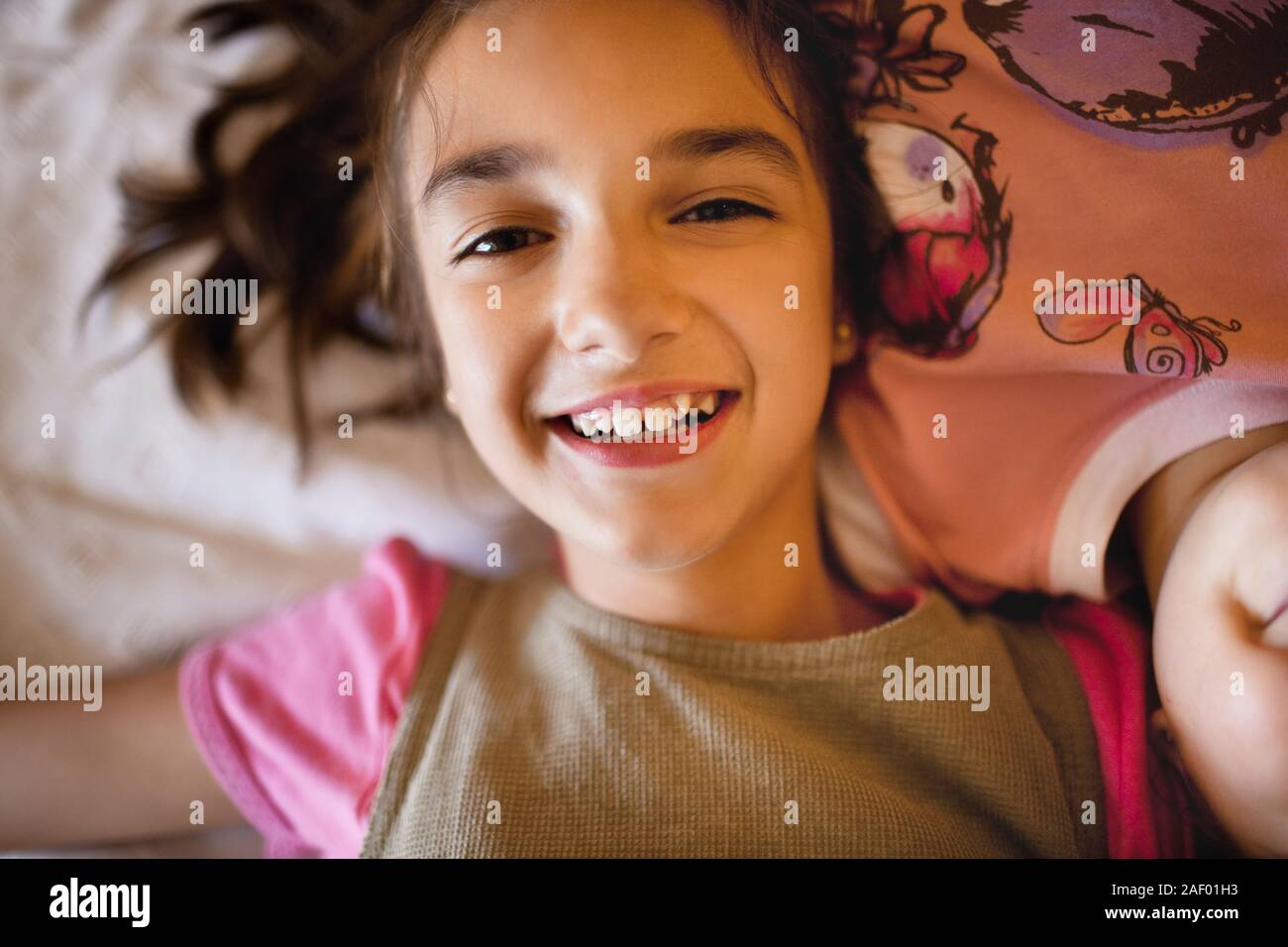 Young girl smiles as she lies on a bed Stock Photo - Alamy