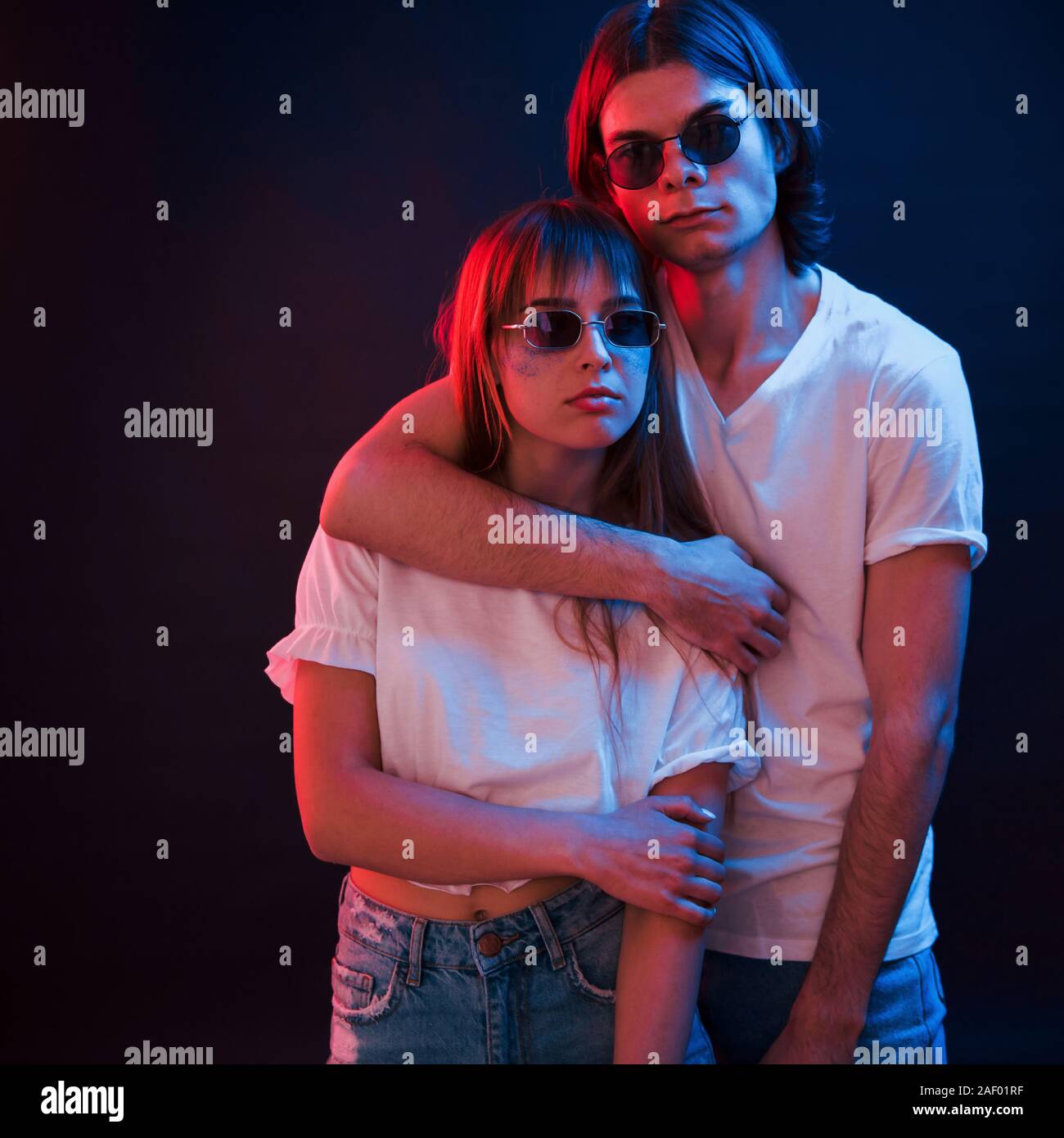 Pure love. Couple standing in dark room with red and blue neon lighting Stock Photo