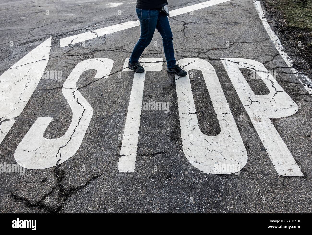 Woman walking over Stop road marking. Stock Photo