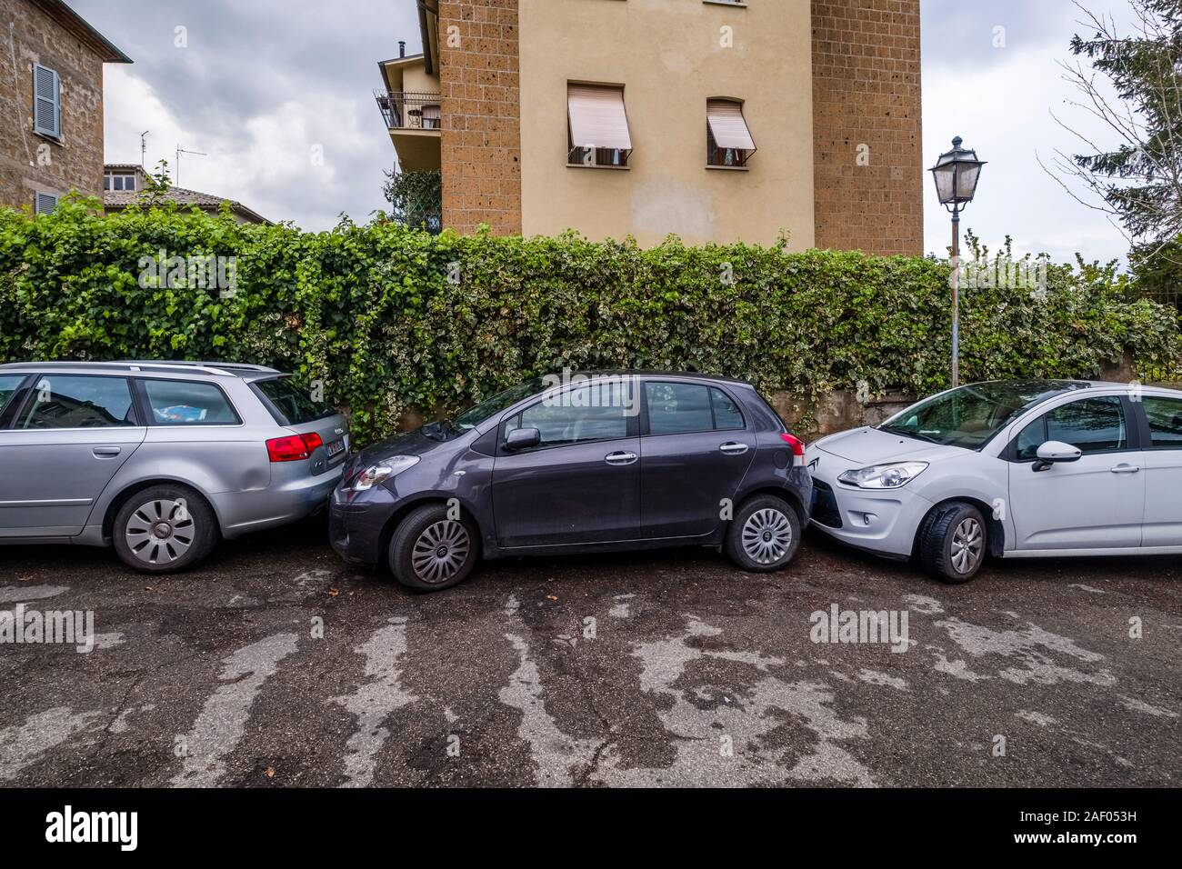 A black car blocked between two othe cars in a parking space at a roadside Stock Photo