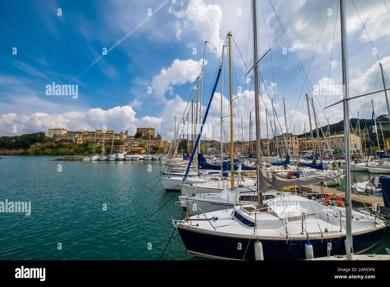 Sailing boats in the harbour at Lake Bolsena, the medieval town with the castle Rocca Farnese in the distance Stock Photo