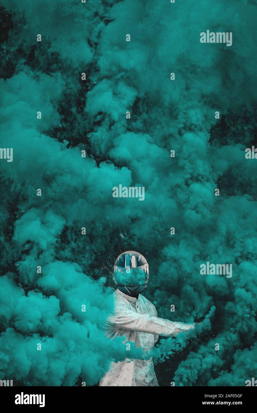guy in mask standing in between blue smoke bombs. vertical Stock Photo