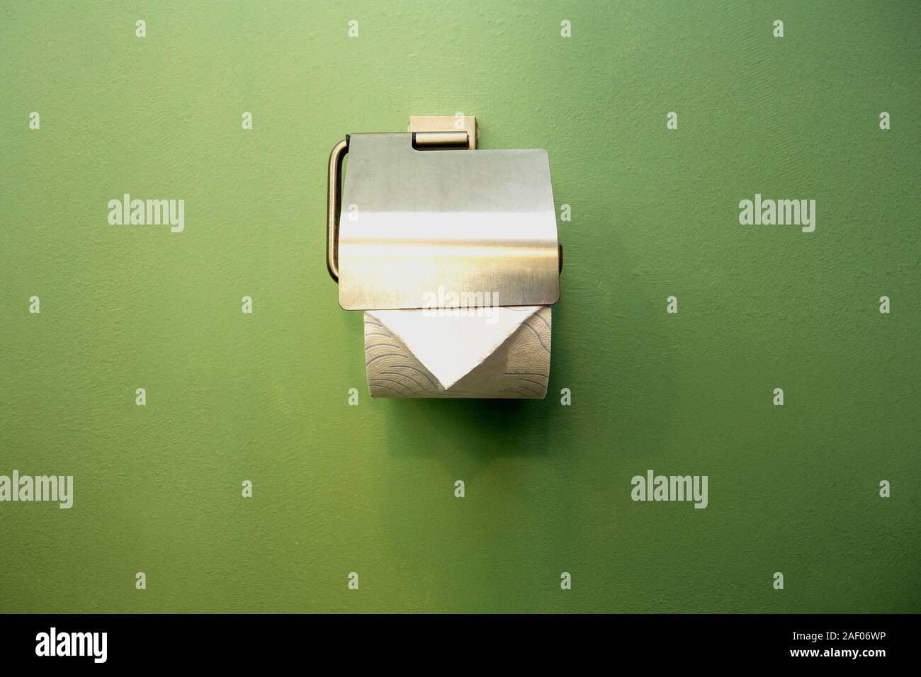 Close-up of toilet roll holder in bathroom near green wall Stock Photo