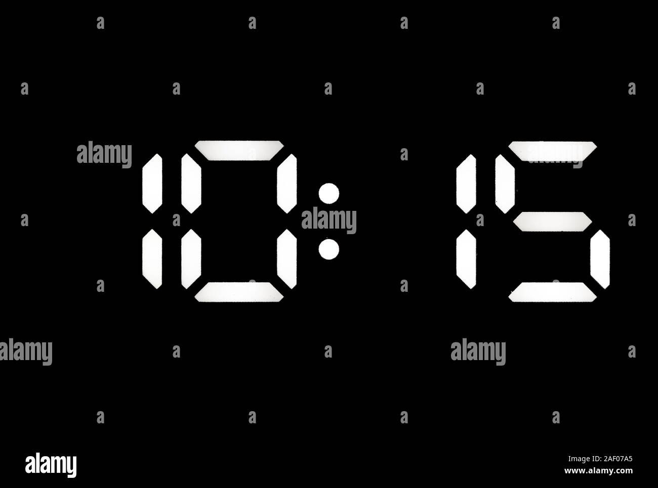 Real white led digital clock on a black background showing time 10:15 Stock Photo