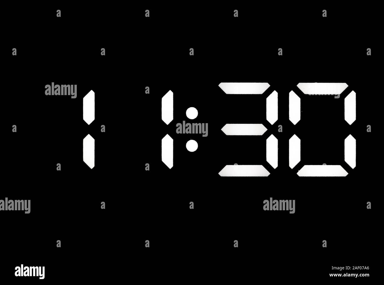 Real white led digital clock on a black background showing time 11:30 Stock Photo