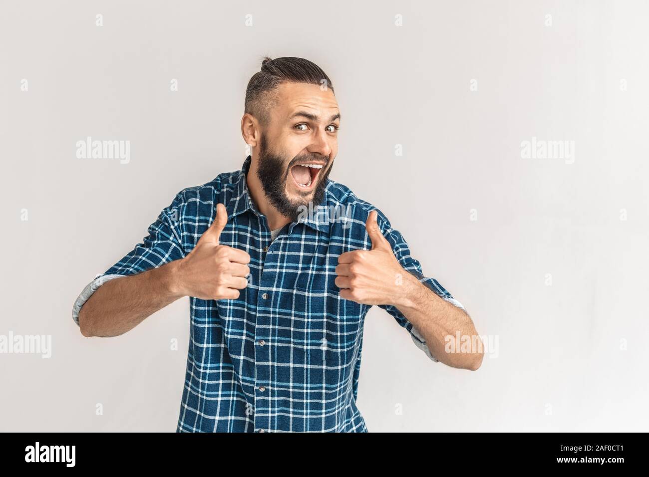 Mature bearded man showing thumbs up, looking at camera Stock Photo