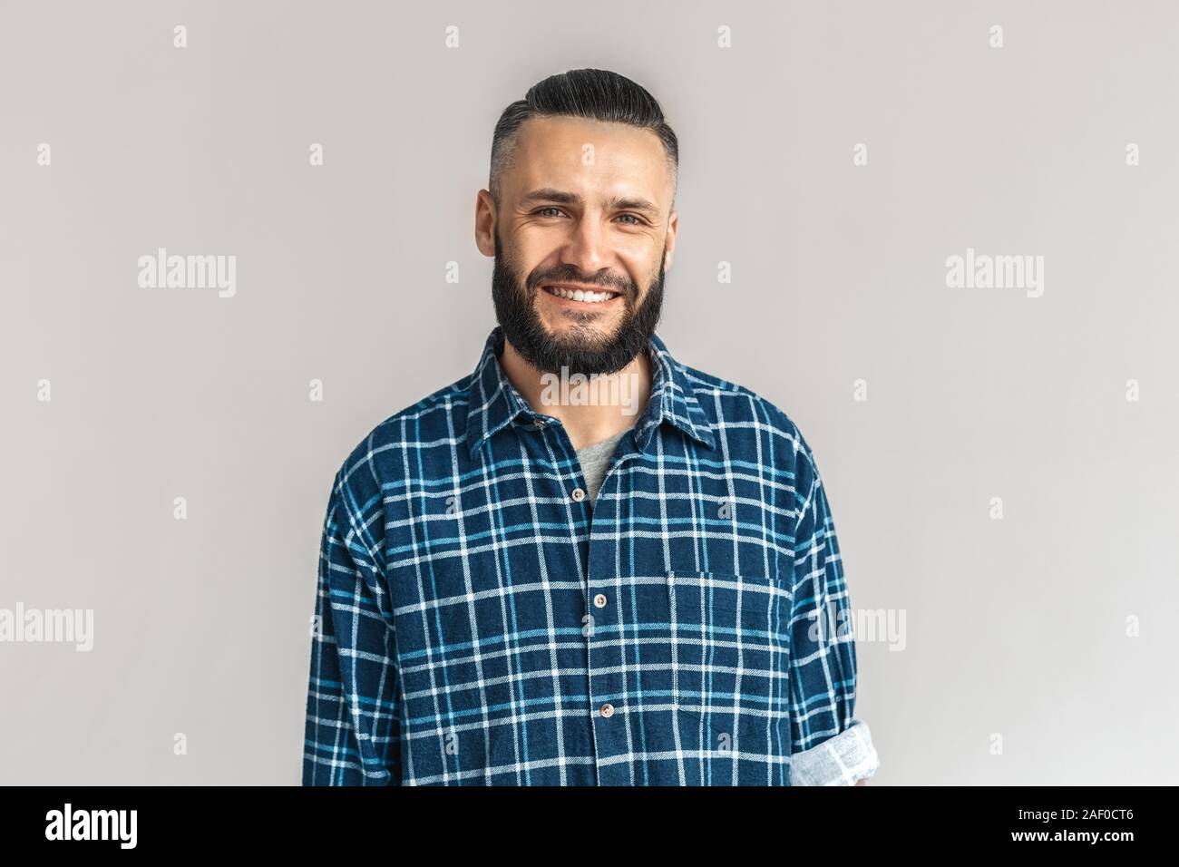 Mature bearded man smiling wide, standing on grey background Stock Photo