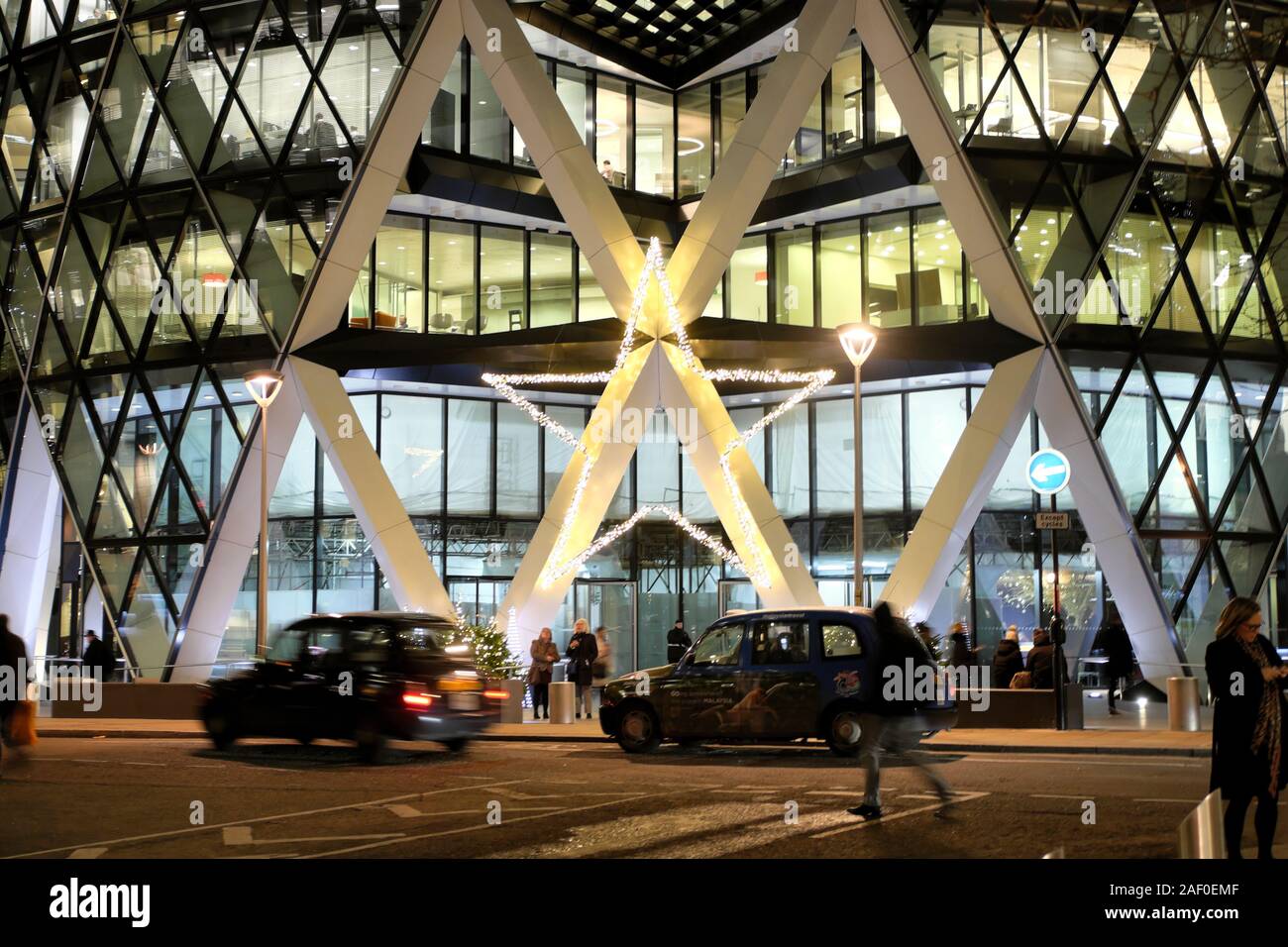Christmas star decoration and taxis outside the entrance to the gherkin skyscraper building in the financial district City of London UK  KATHY DEWITT Stock Photo