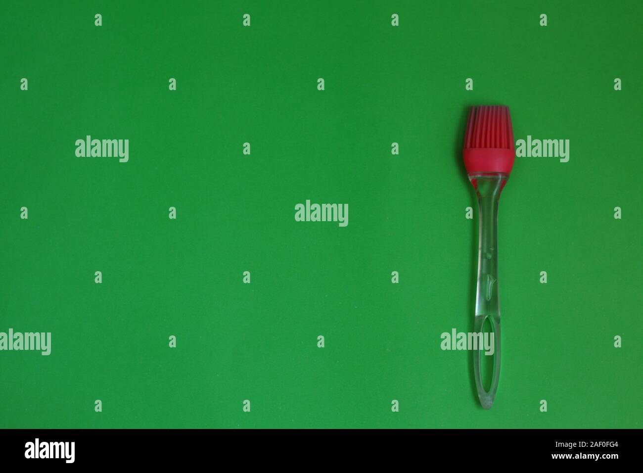 Red kitchen silicone brush on a green background Stock Photo