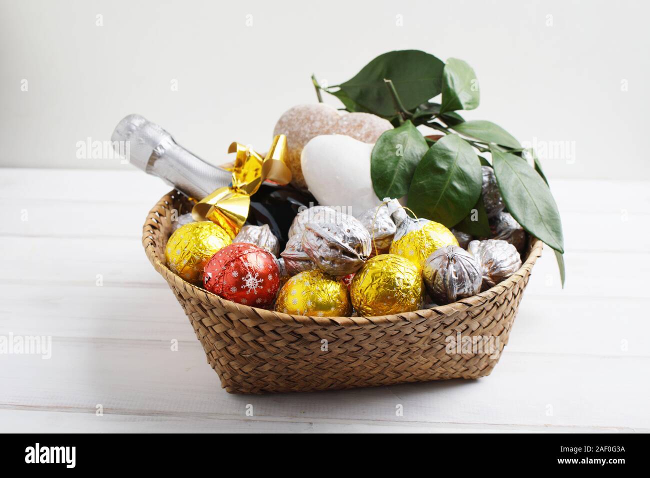Christmas gift basket with chocolate candies, walnuts, gingerbread, mandarin oranges, and a bottle of champagne Stock Photo