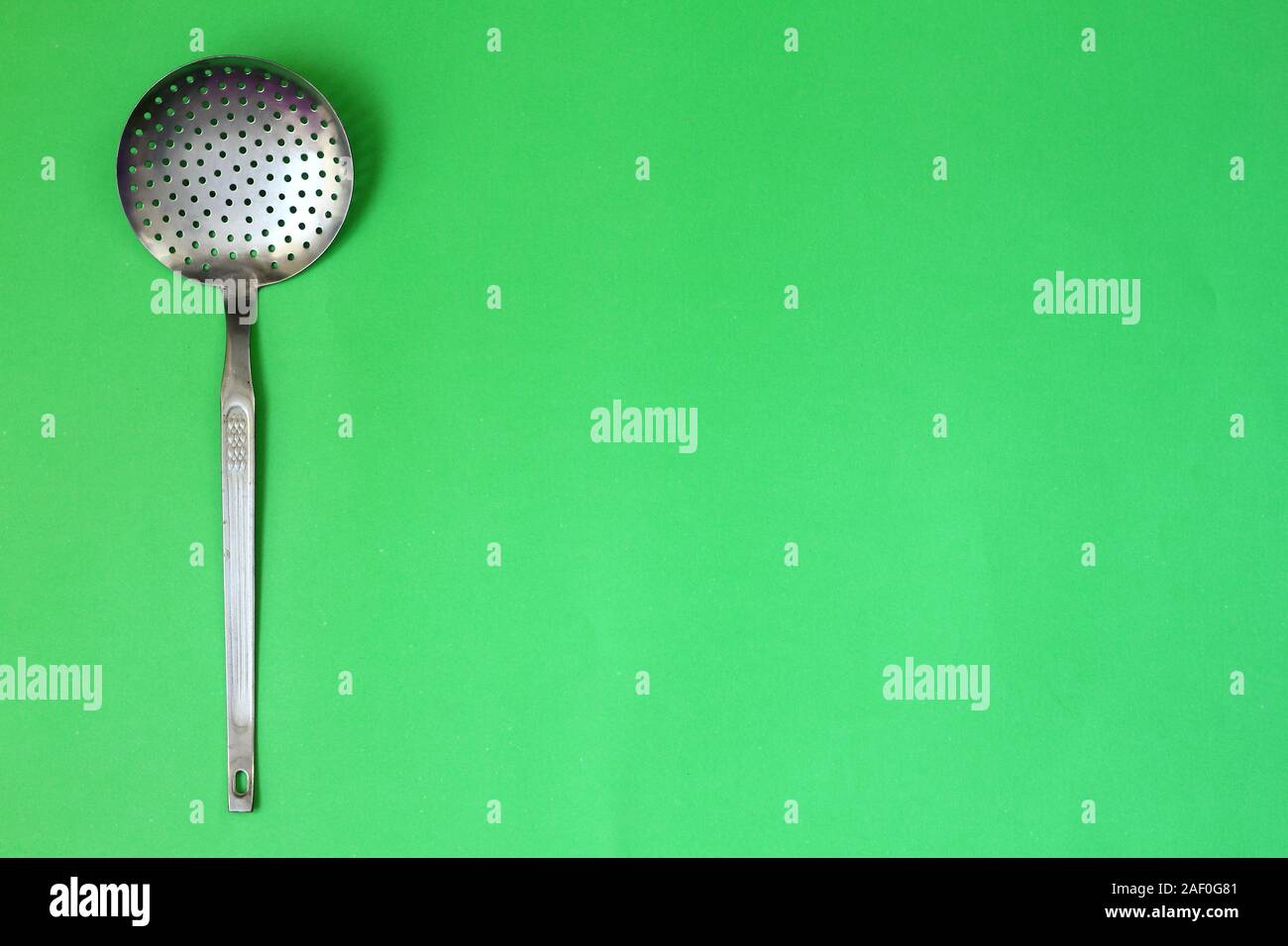 A metal colander isolated on a green background Stock Photo Alamy