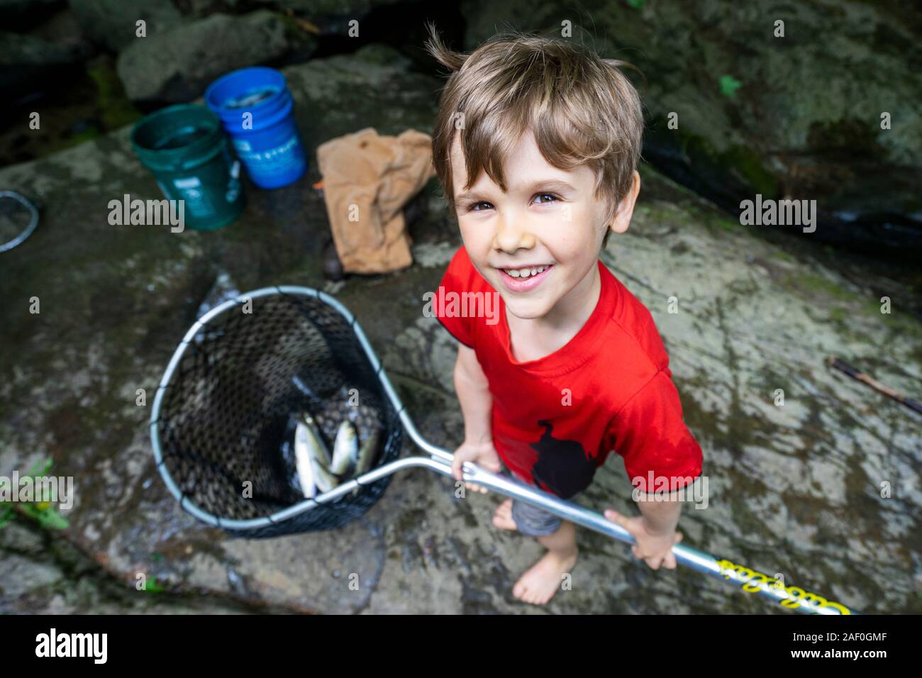 Young boy holding fishing net with fish Stock Photo