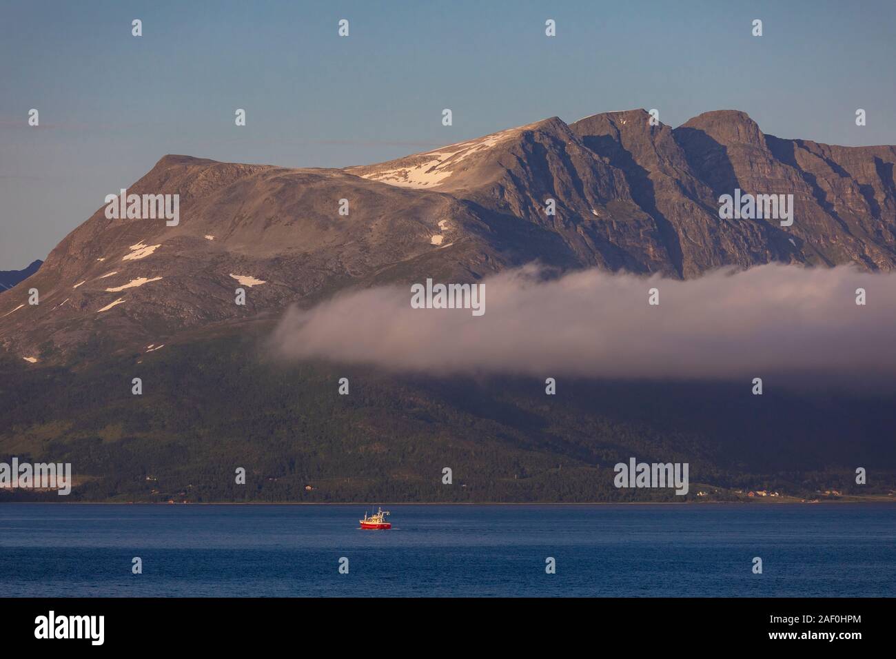 TROMS, NORWAY - Boat passes by mountains, on Straumsfjorden fjord, northern Norway. Stock Photo