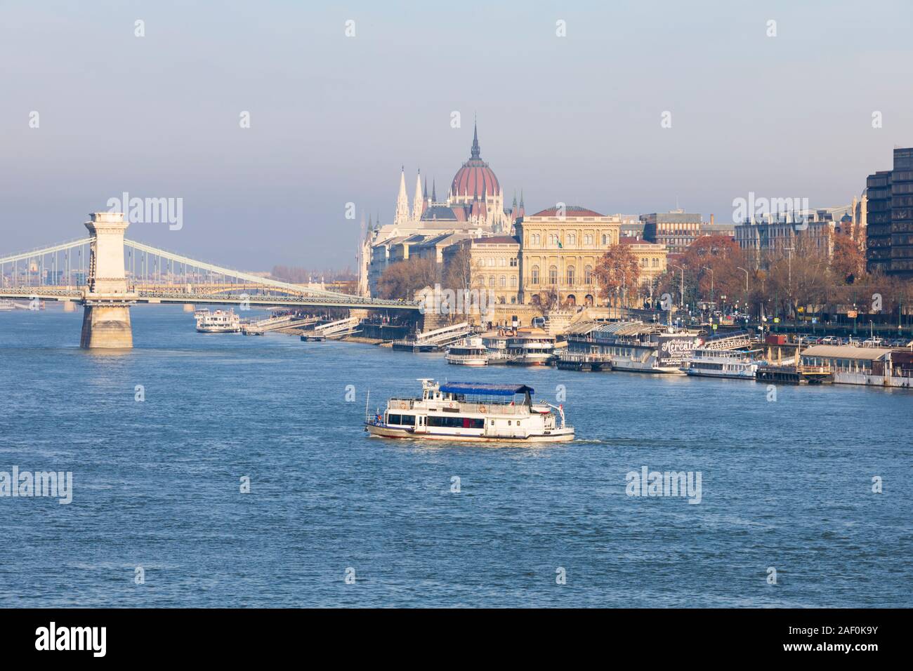 River Danube cruise ship passes under the Chain Bridge with the Parliament building behind. Budapest, Hungary. December 2019 Stock Photo