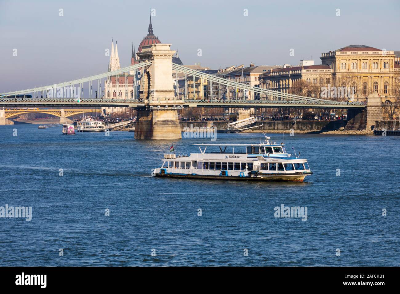 River Danube cruise ship passes under the Chain Bridge with the Parliament building behind. Budapest, Hungary. December 2019 Stock Photo
