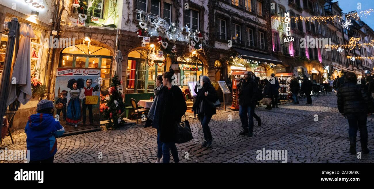 Strasbourg, France - Dec 24, 2018: Wide anlge view of vibrant pedestrian iconic with tourists people walking discovering the annual Christmas Market decorations and Palais Rohan hotel in background Stock Photo