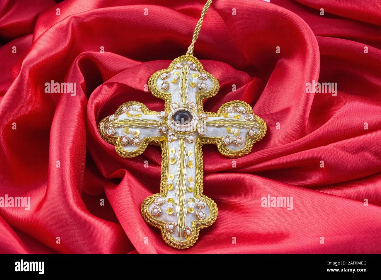 gold hand made cross on red background Stock Photo