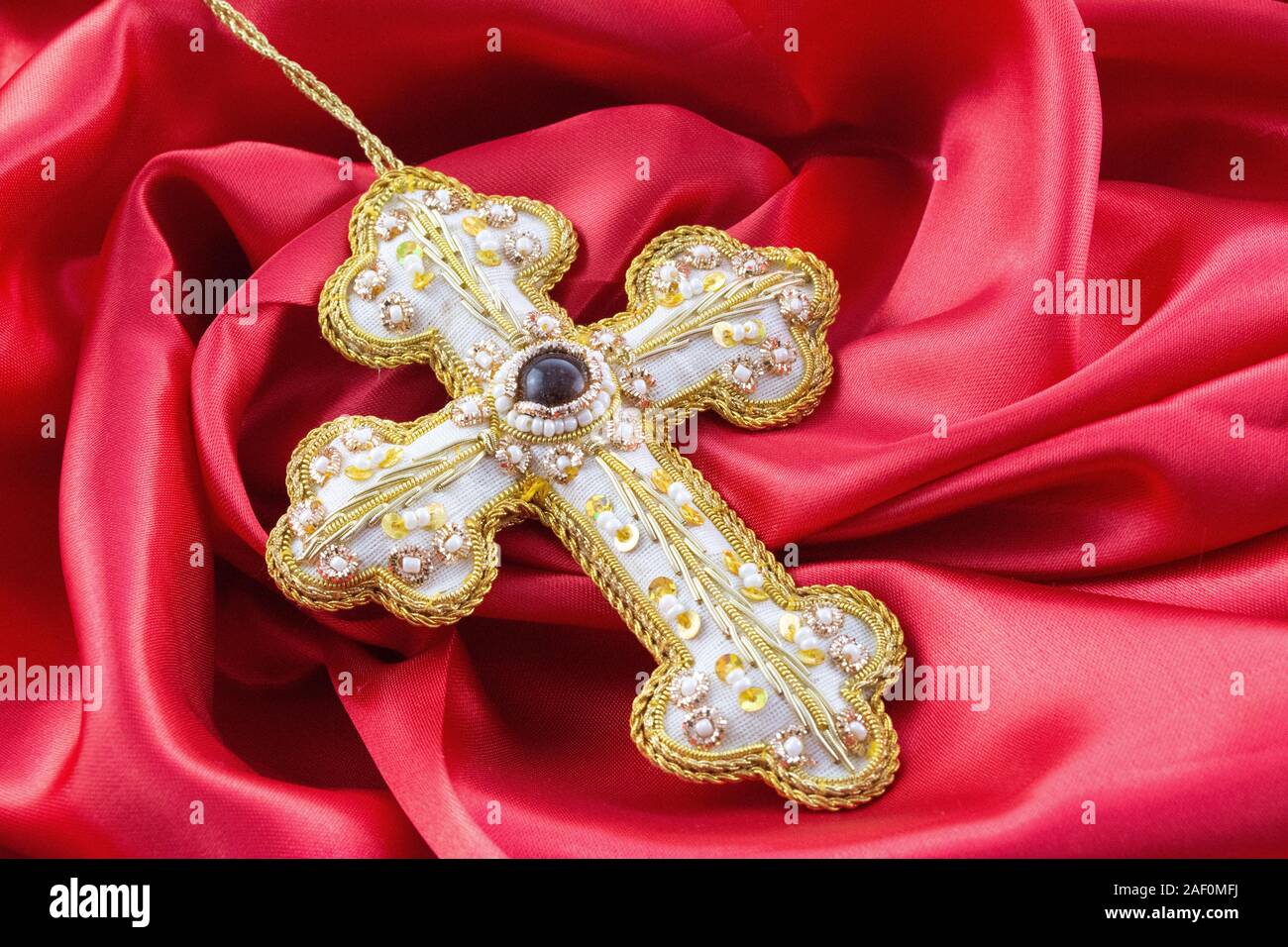 gold hand made cross on red background Stock Photo
