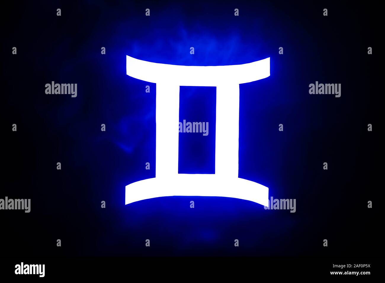 blue illuminated Gemini zodiac sign with colorful smoke on background ...