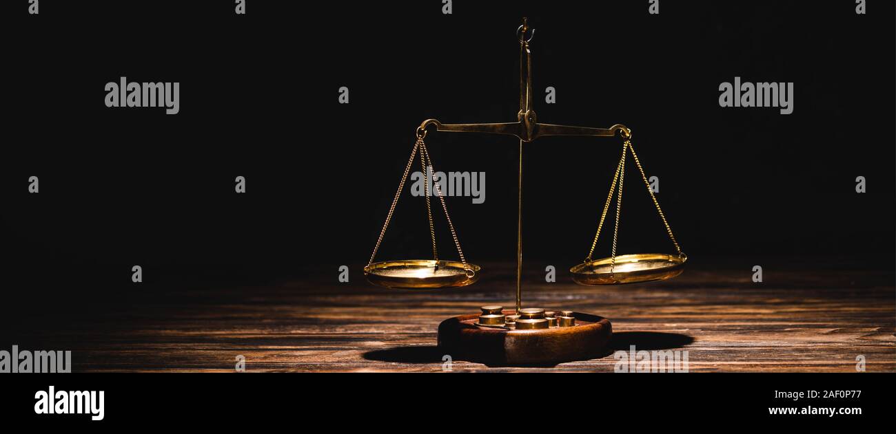 golden scales of justice on wooden table on black background Stock ...