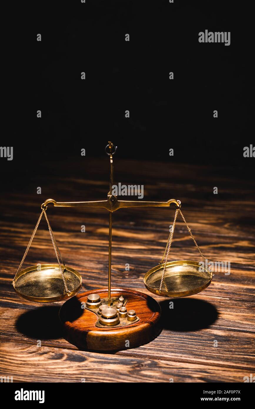 golden scales of justice on wooden table on black background Stock ...