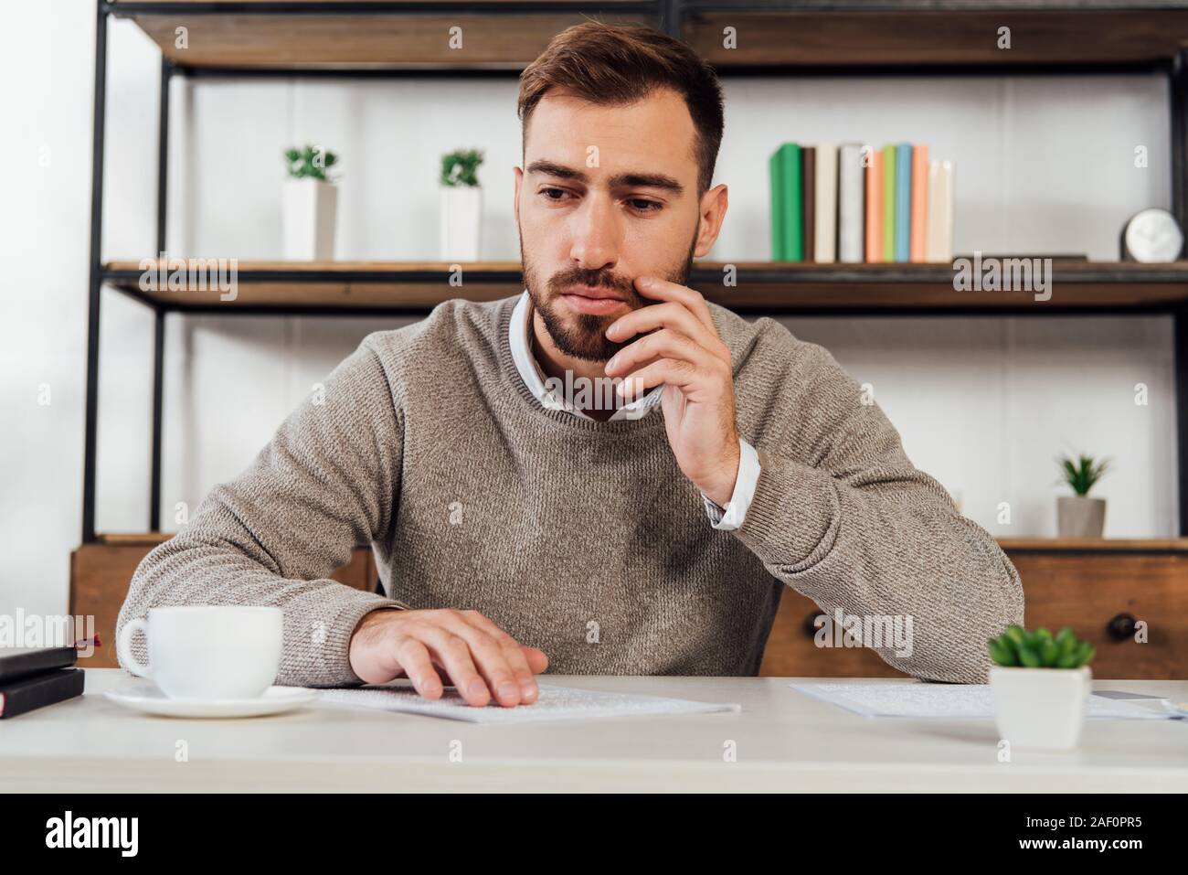 Pensive blind man reading at table beside coffee cup Stock Photo